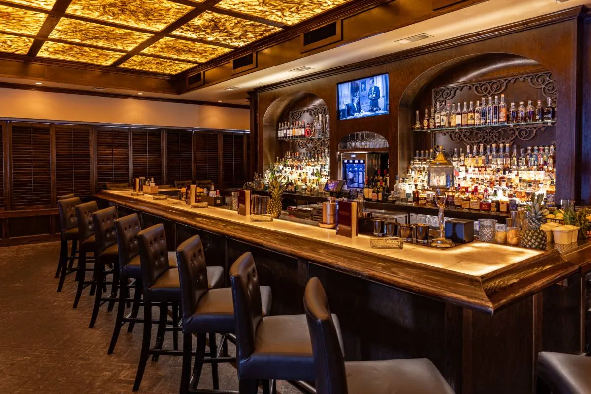 The illuminated bar, leather barstools and shuttered lounge wall at Red Phone Booth Buckhead
