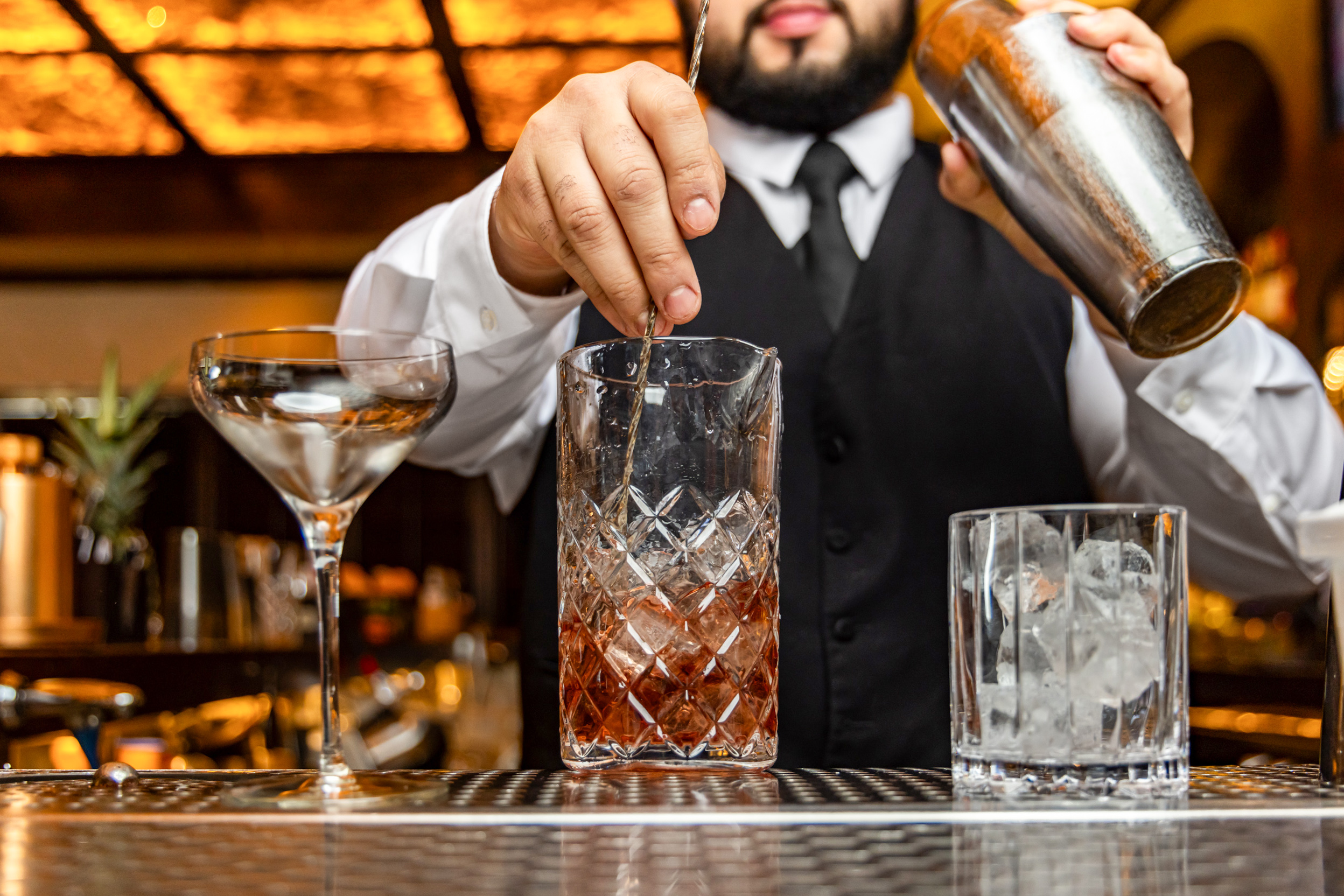 A Red Phone Booth bartender stirring a cocktail at the bar.