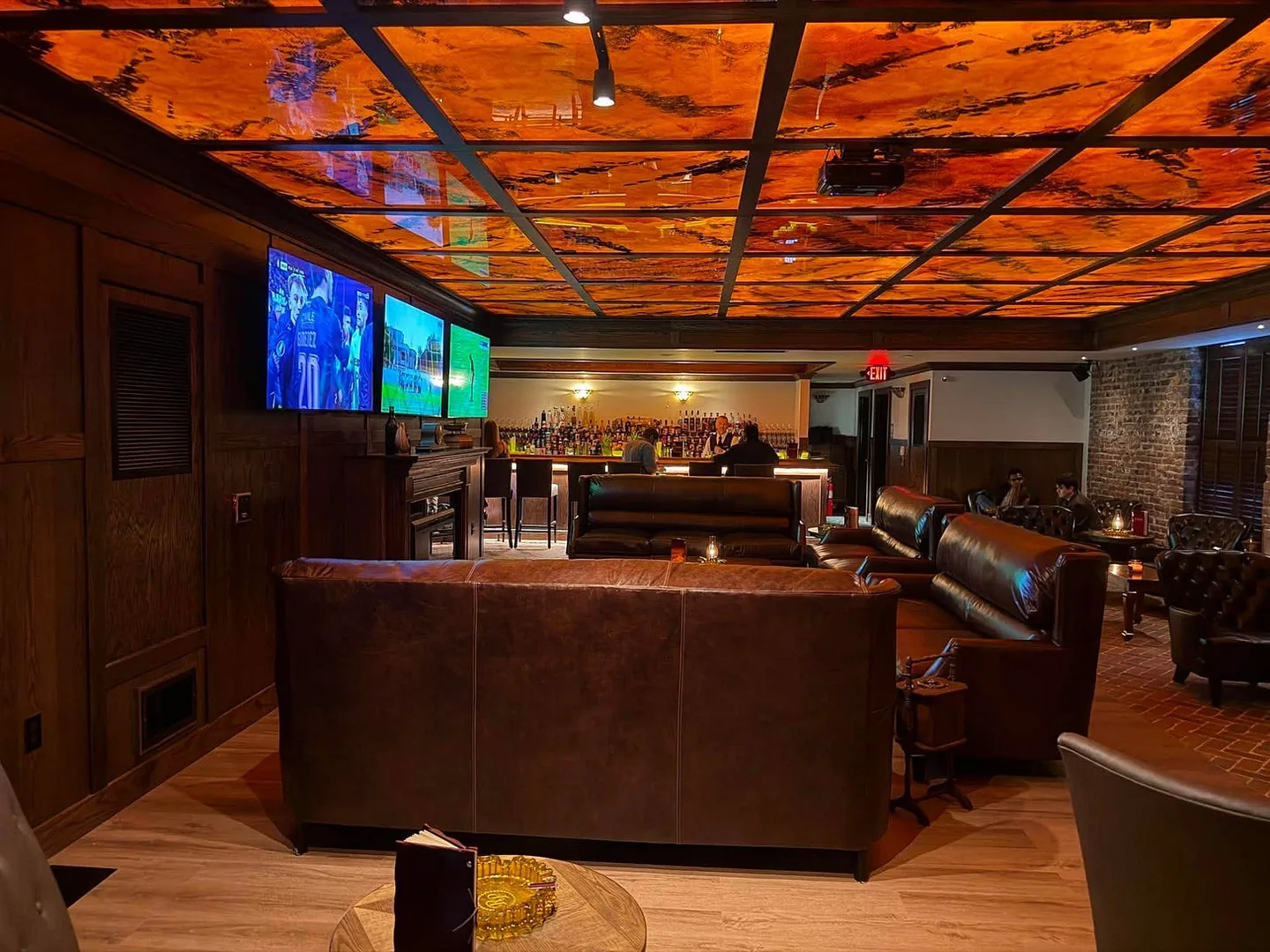 Leather sofas and the bar beneath the amber ceiling in the upstairs lounge at Red Phone Booth Durham