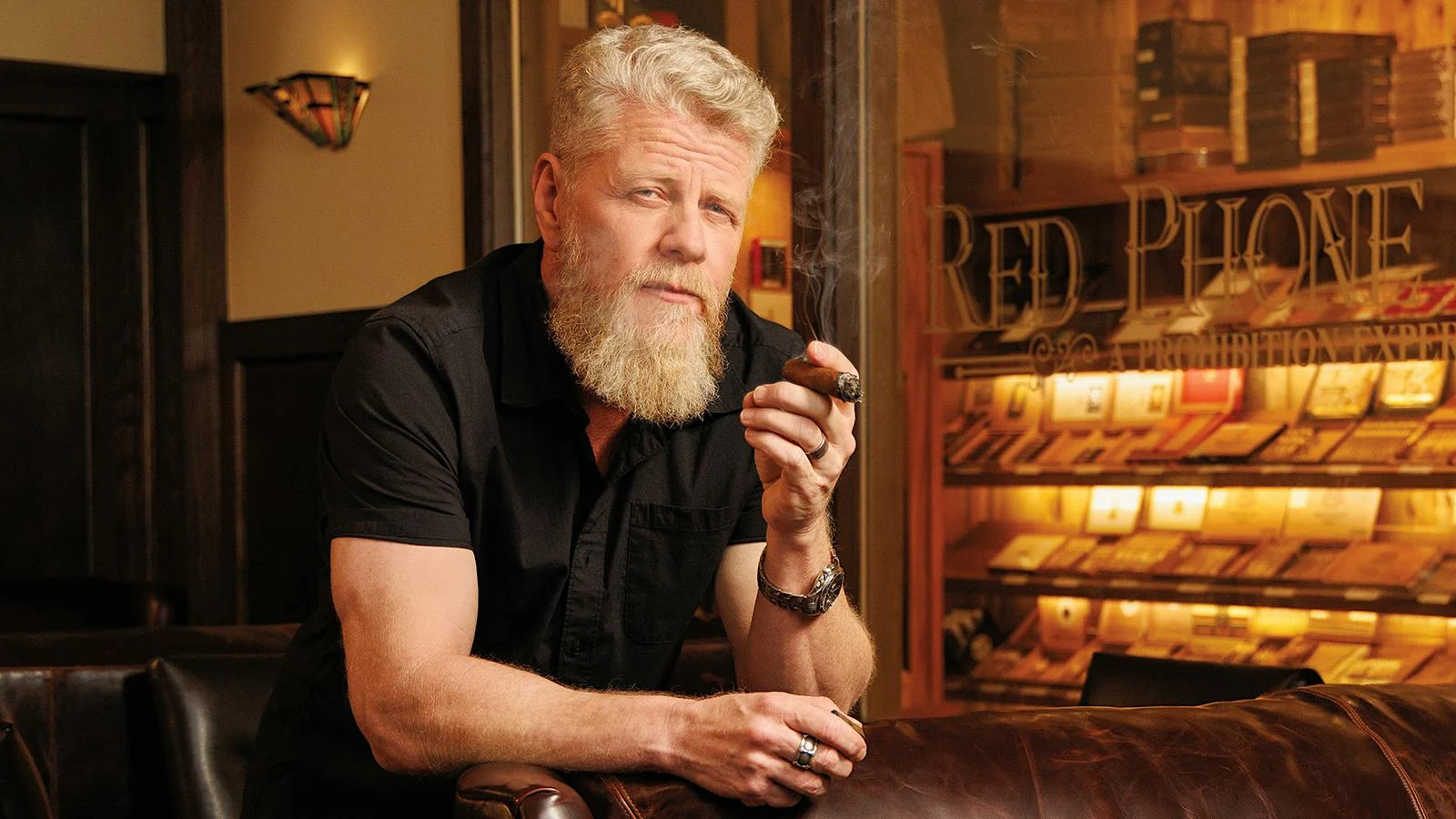 Michael Cudlitz holding a cigar beside the Red Phone Booth humidor.